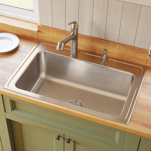 Stainless steel single-bowl kitchen sink set into a wood countertop