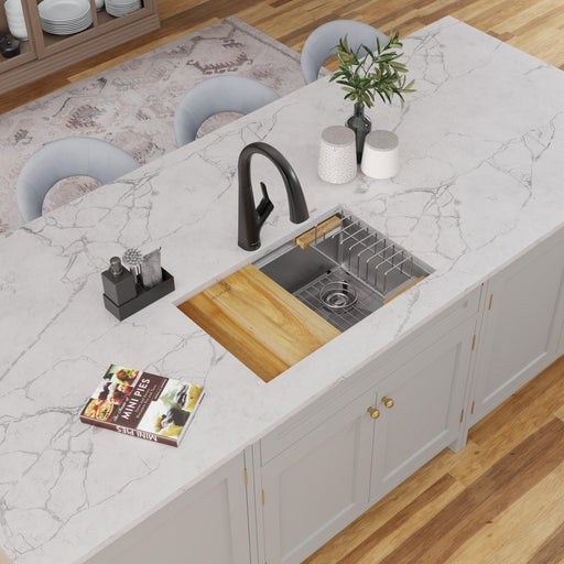 Stainless steel workstation sink with wood cutting board in a white kitchen countertop