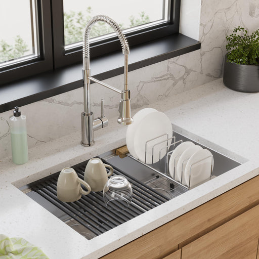Stainless steel kitchen sink fitted with a drying rack holding plates