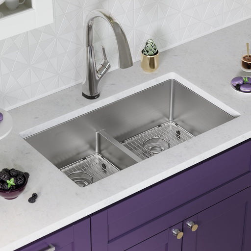 Stainless steel double-bowl workstation sink installed above purple kitchen cabinets