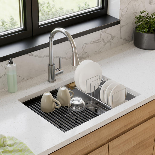 Stainless steel drying rack holding dishes over a kitchen sink