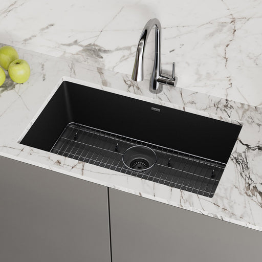 Large black single-bowl quartz kitchen sink fitted with a protective grid
