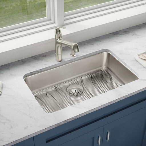 Stainless steel Elkay kitchen sink and faucet installed beneath a window
