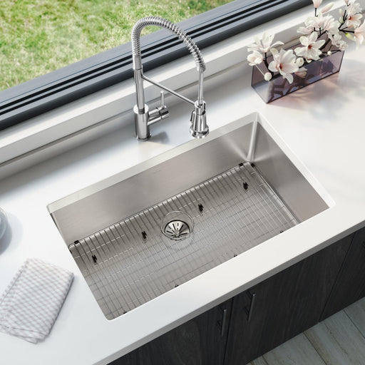 Stainless steel kitchen sink installed beneath a window with a pull-down faucet