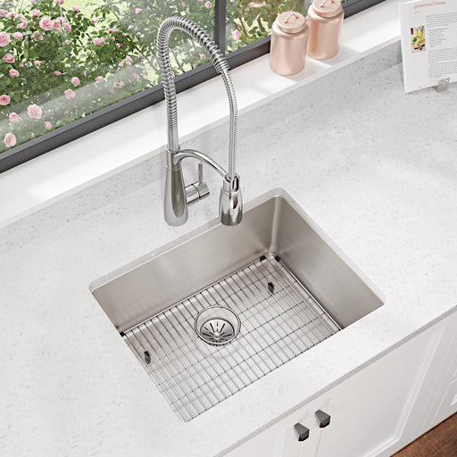 Stainless steel bottom grid fitted into a small kitchen sink beneath a window