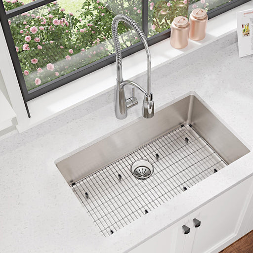 Stainless steel sink bottom grid fitted into a kitchen sink beneath a window