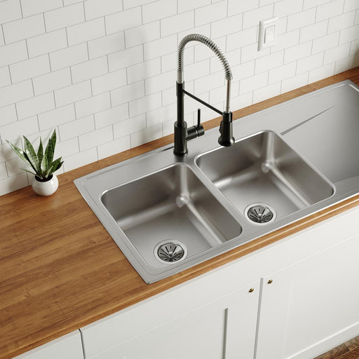 Long double-bowl stainless steel sink with drainboard installed in a wood countertop