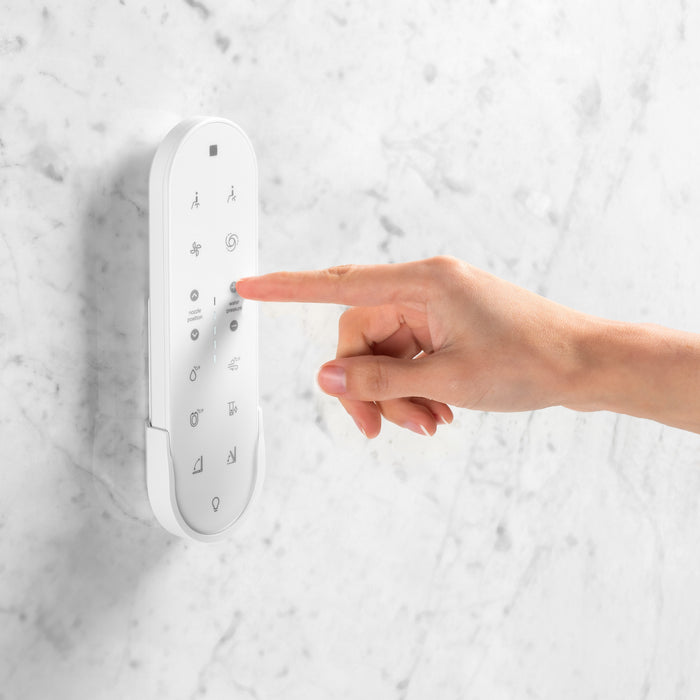 Brondell KBT-900 hand pressing a button on the Coit remote mounted on a marble-patterned wall