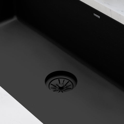 Close-up of a dark strainer drain in a black kitchen sink