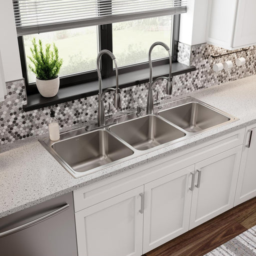 Triple-bowl stainless steel sink installed beneath a kitchen window